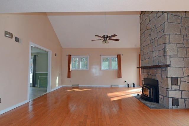 unfurnished living room featuring high vaulted ceiling, light wood-type flooring, a wood stove, and ceiling fan