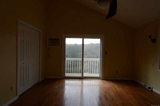 unfurnished room featuring high vaulted ceiling, a wall unit AC, and wood-type flooring