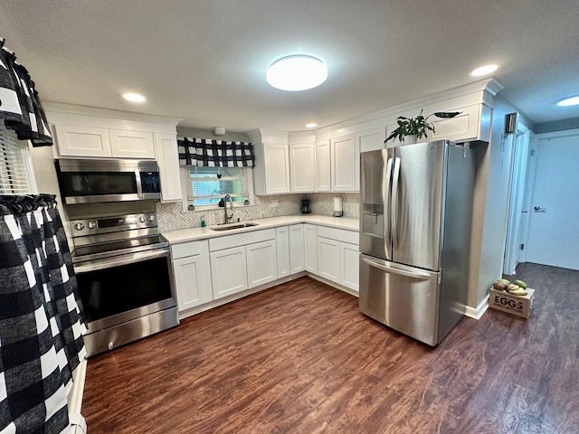 kitchen with dark wood-type flooring, stainless steel appliances, backsplash, sink, and white cabinets