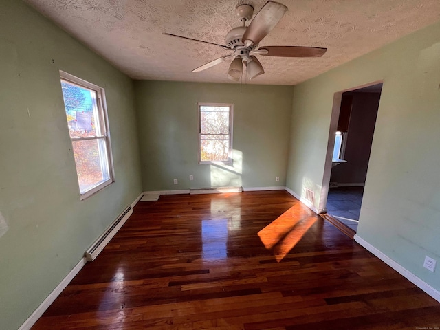 unfurnished room featuring dark hardwood / wood-style flooring, a textured ceiling, baseboard heating, and plenty of natural light