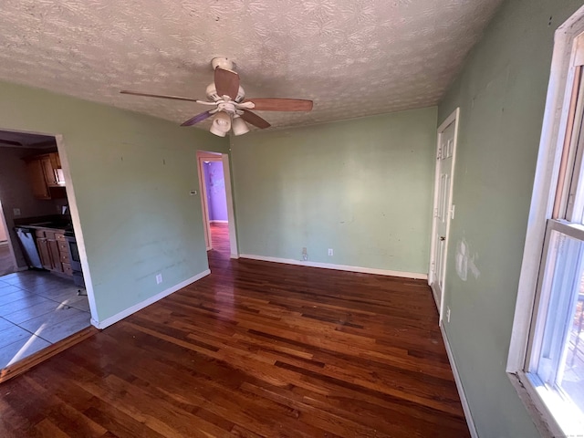 spare room with dark wood-type flooring, a textured ceiling, and ceiling fan