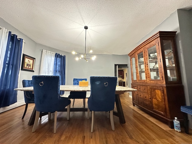 dining area with dark wood-type flooring, a notable chandelier, and a textured ceiling