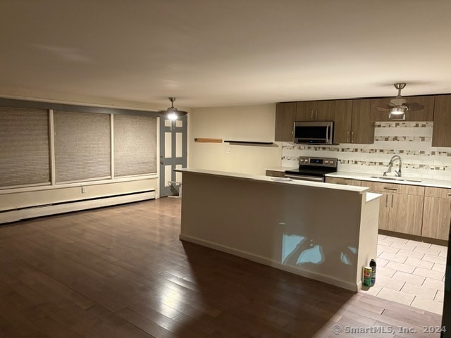 kitchen with tasteful backsplash, sink, light wood-type flooring, stainless steel appliances, and decorative light fixtures