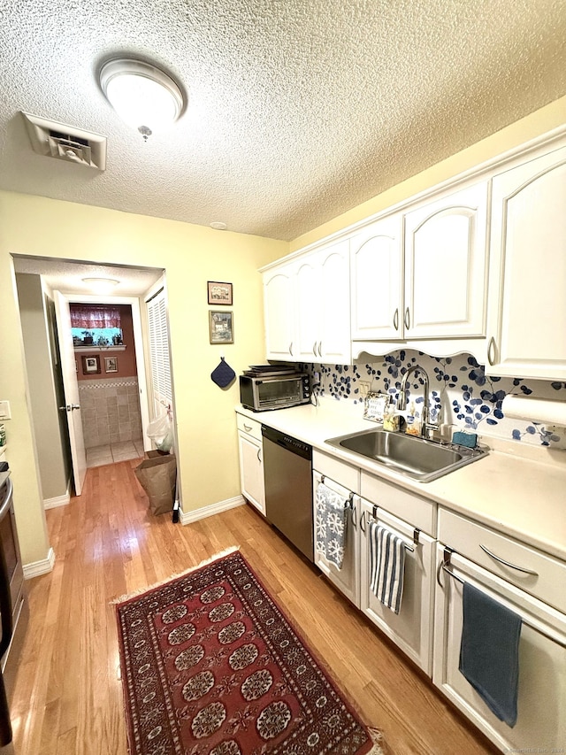 kitchen featuring sink, dishwasher, light wood-type flooring, a textured ceiling, and white cabinetry