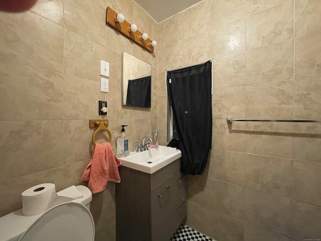 bathroom featuring vanity, toilet, and tile walls