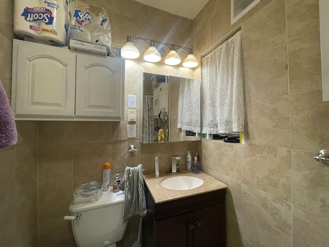 bathroom featuring vanity, toilet, tile walls, and tasteful backsplash