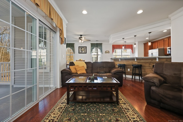 living room with ornamental molding, dark wood-type flooring, and ceiling fan