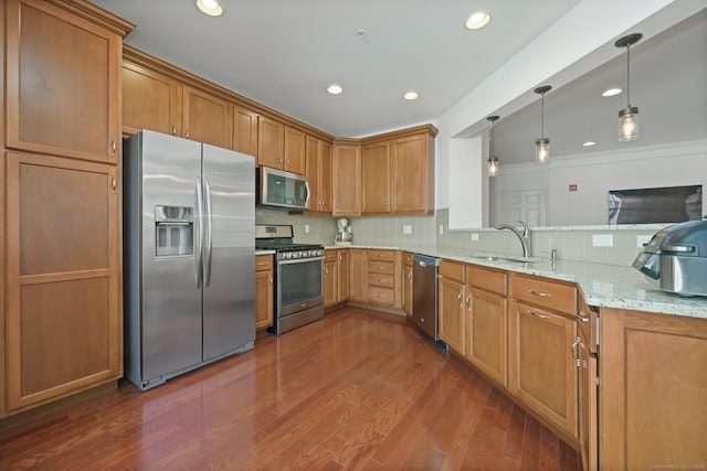 kitchen with stainless steel appliances, sink, light stone counters, pendant lighting, and dark hardwood / wood-style flooring