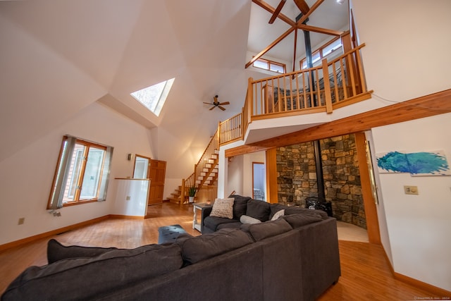 living room featuring a wood stove, high vaulted ceiling, ceiling fan, and light wood-type flooring