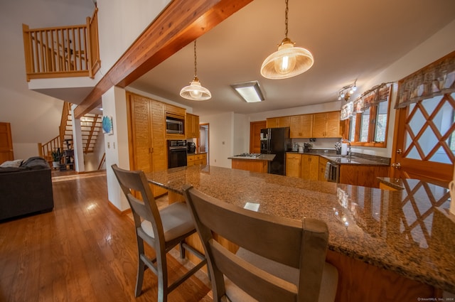 kitchen featuring wood-type flooring, black appliances, kitchen peninsula, and decorative light fixtures