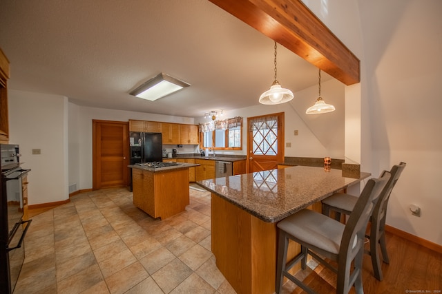 kitchen with a breakfast bar, kitchen peninsula, stainless steel dishwasher, pendant lighting, and black fridge with ice dispenser