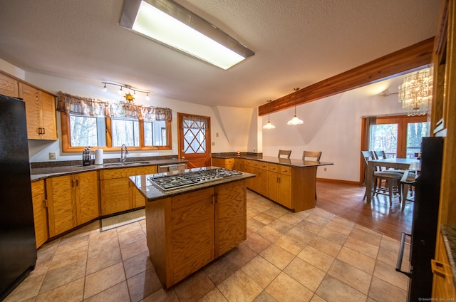 kitchen with sink, decorative light fixtures, appliances with stainless steel finishes, and a center island