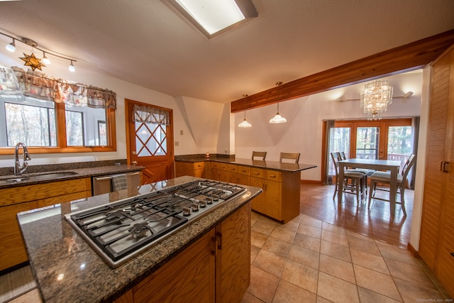 kitchen featuring stainless steel appliances, wooden walls, sink, light tile patterned floors, and decorative light fixtures