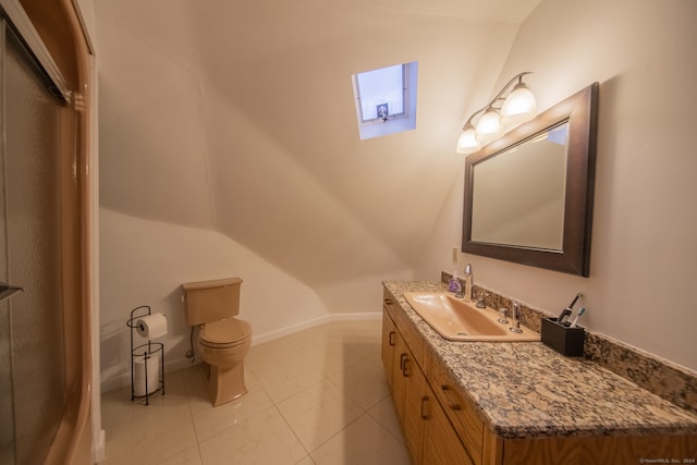 bathroom featuring toilet, vanity, vaulted ceiling, and tile patterned floors