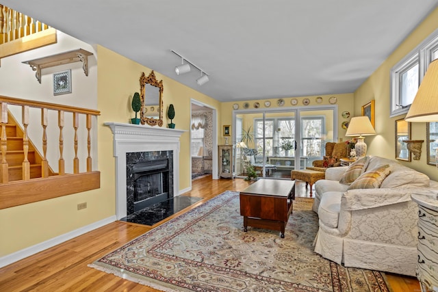 living room with a high end fireplace, hardwood / wood-style floors, and track lighting