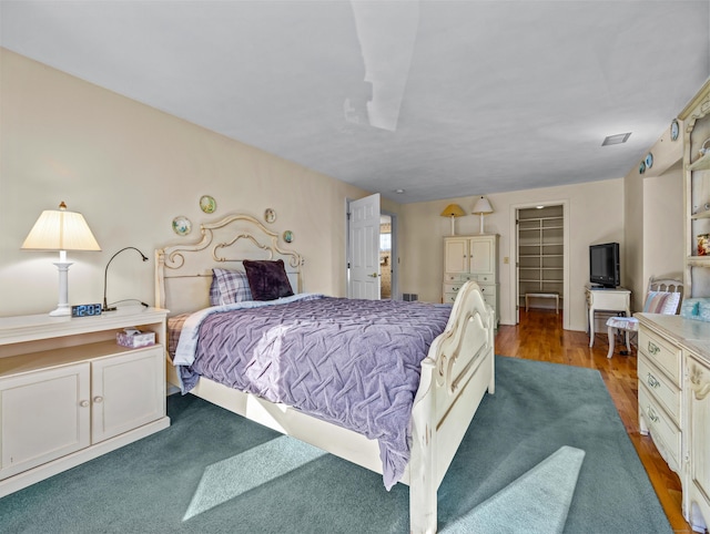 bedroom with wood-type flooring and a spacious closet