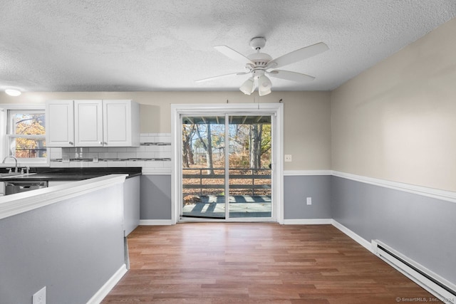 unfurnished dining area with a baseboard heating unit, hardwood / wood-style floors, and plenty of natural light