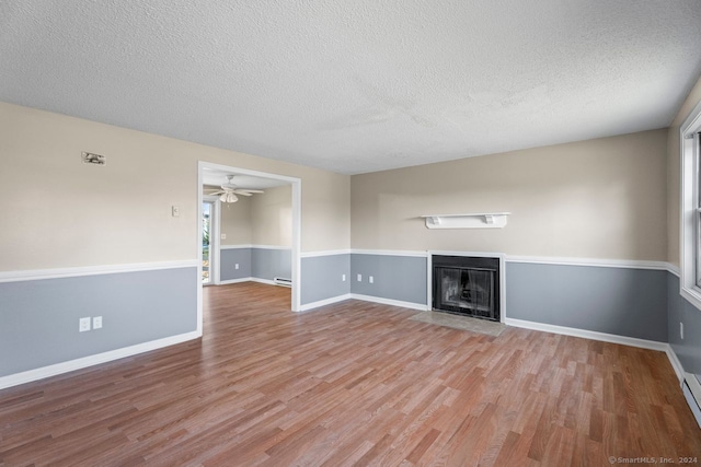 unfurnished living room featuring ceiling fan, a wealth of natural light, a textured ceiling, and light hardwood / wood-style floors