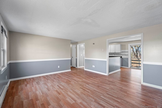 empty room with a textured ceiling and light hardwood / wood-style flooring