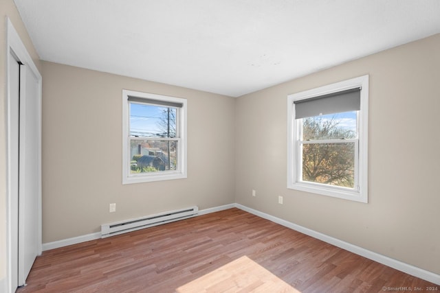 unfurnished bedroom with a baseboard radiator, a closet, and light wood-type flooring