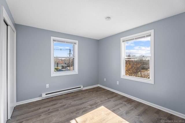 unfurnished bedroom with multiple windows, a baseboard radiator, a closet, and dark hardwood / wood-style flooring