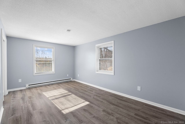 empty room with dark wood-type flooring, a textured ceiling, and a baseboard heating unit