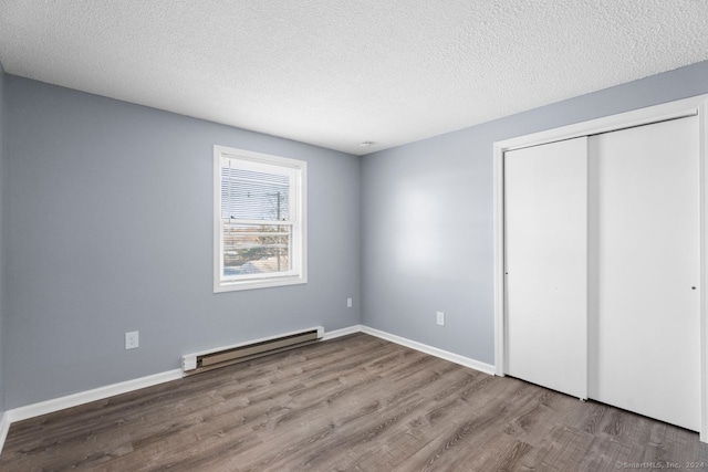 unfurnished bedroom with hardwood / wood-style flooring, a baseboard radiator, a closet, and a textured ceiling