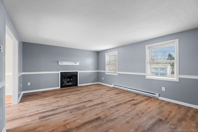 unfurnished living room with a textured ceiling, light wood-type flooring, and a baseboard heating unit