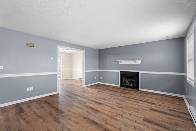 unfurnished living room with hardwood / wood-style flooring, a baseboard radiator, and a textured ceiling