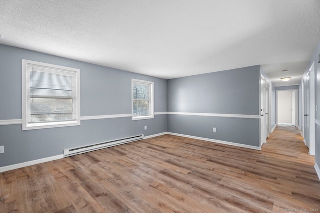 unfurnished room featuring a baseboard radiator, light hardwood / wood-style flooring, and a textured ceiling