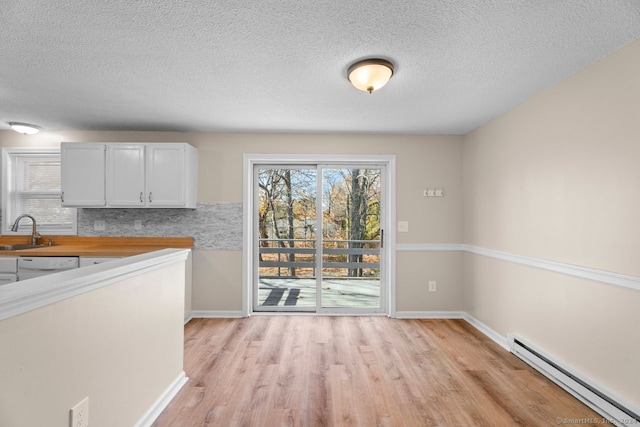 kitchen with a baseboard radiator, a textured ceiling, sink, white cabinetry, and light hardwood / wood-style flooring