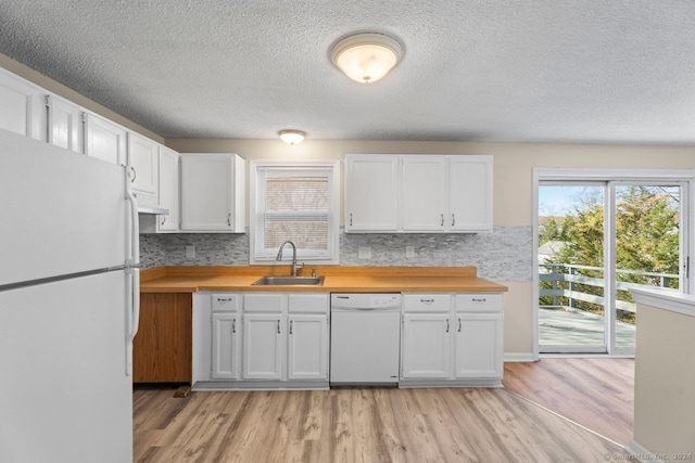 kitchen featuring white cabinetry, decorative backsplash, sink, light hardwood / wood-style floors, and white appliances