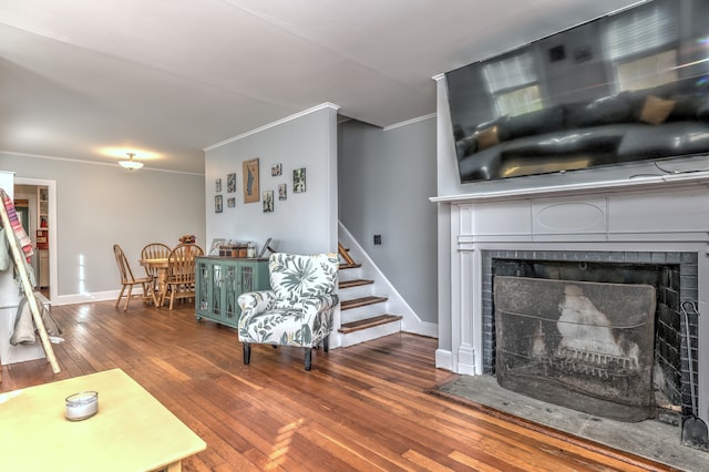 living room featuring a fireplace, wood-type flooring, and ornamental molding