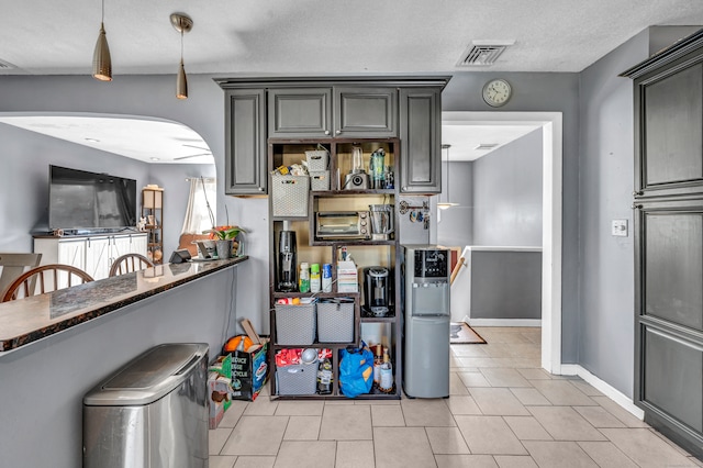 kitchen with a textured ceiling, light tile patterned floors, and pendant lighting