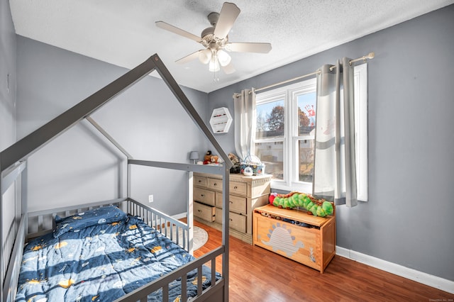 bedroom with a textured ceiling, hardwood / wood-style floors, and ceiling fan