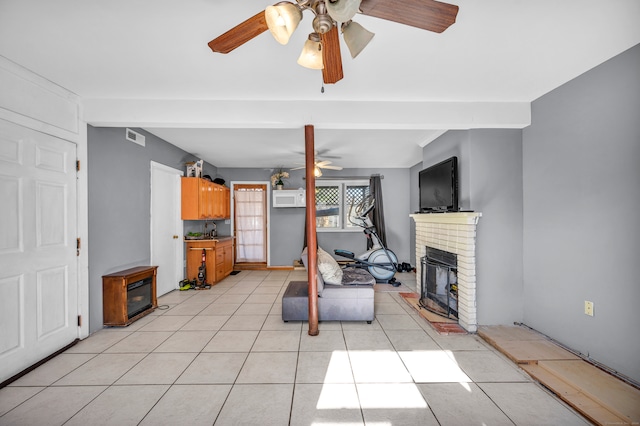 tiled living room featuring a brick fireplace, a wall unit AC, ceiling fan, and sink