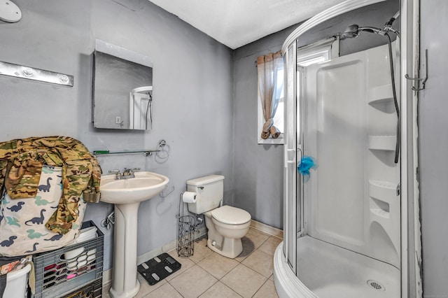 bathroom with walk in shower, toilet, sink, and tile patterned flooring