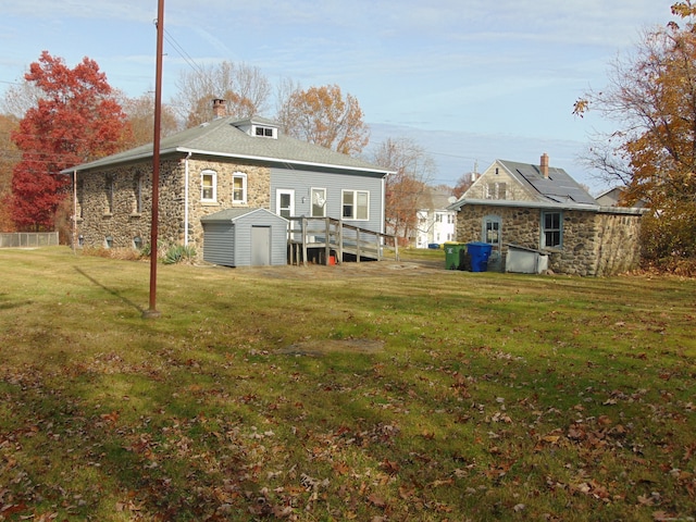 rear view of house featuring a yard, a deck, and a storage shed