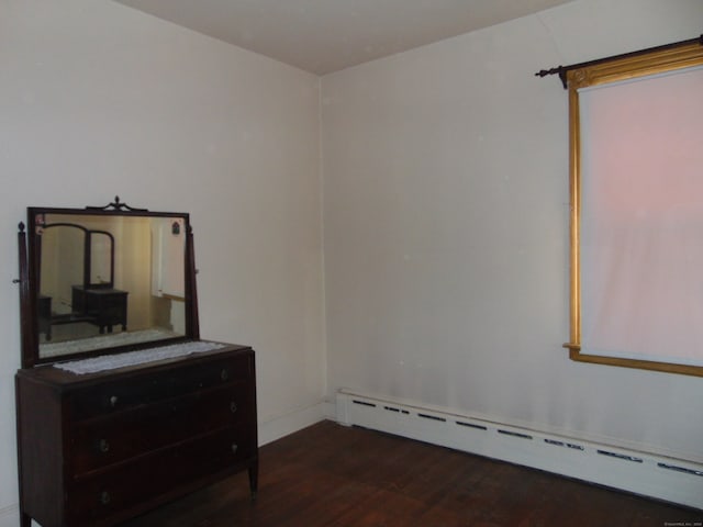 bedroom with dark wood-type flooring and a baseboard heating unit