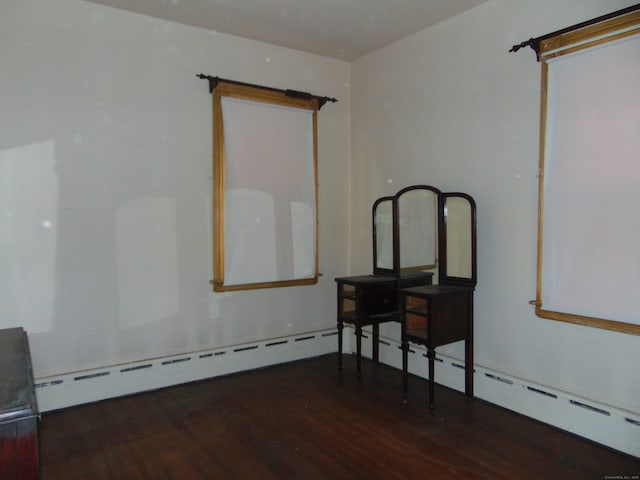 empty room featuring dark wood-type flooring and a baseboard heating unit