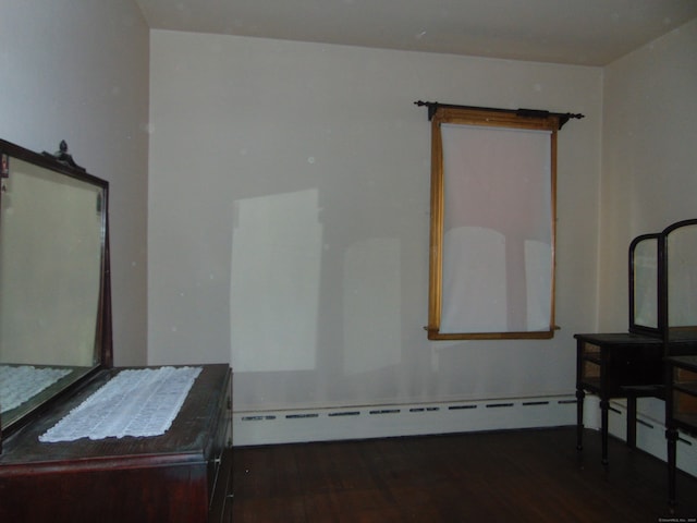 interior space with a baseboard heating unit and dark wood-type flooring