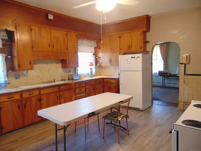 kitchen with light hardwood / wood-style floors, ceiling fan, backsplash, white appliances, and a baseboard radiator