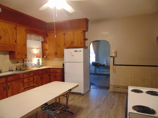 kitchen featuring sink, light hardwood / wood-style floors, a baseboard radiator, white appliances, and ceiling fan