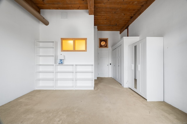 unfurnished living room with light colored carpet, wood ceiling, and a towering ceiling