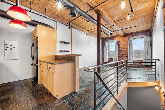 kitchen with black refrigerator, brick wall, light brown cabinets, and wood ceiling