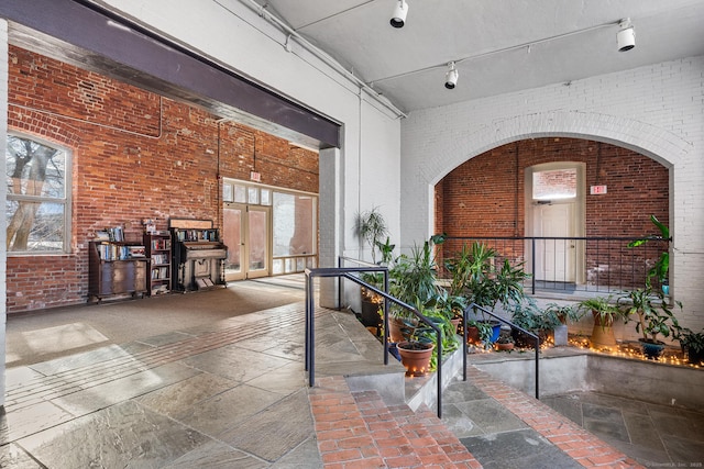 hallway with french doors, brick wall, and a towering ceiling