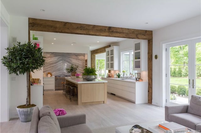 kitchen featuring a kitchen breakfast bar, sink, a center island, light wood-type flooring, and white cabinetry