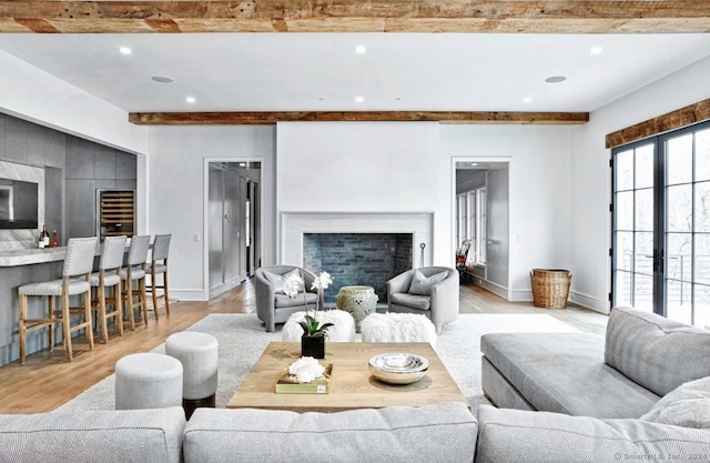 living room with french doors, beam ceiling, and light wood-type flooring