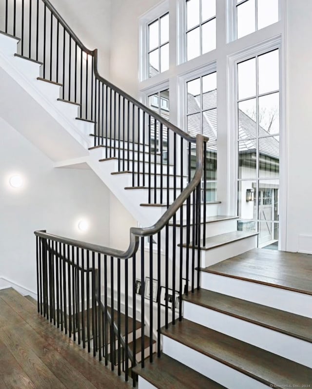 stairs with hardwood / wood-style floors and a high ceiling