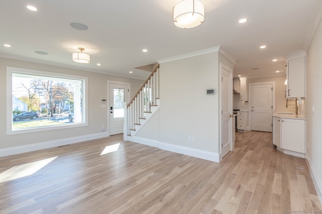 unfurnished living room featuring plenty of natural light, ornamental molding, and light wood-type flooring